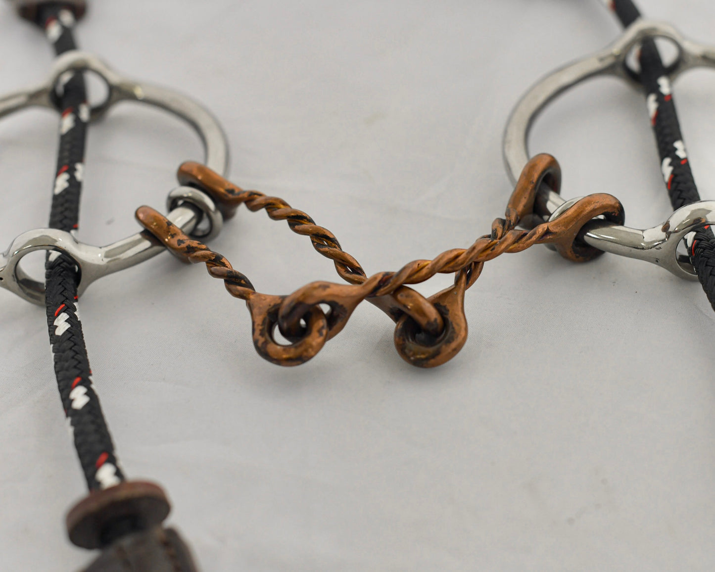 Close up of copper twist barry gag horse bit on a white surface.