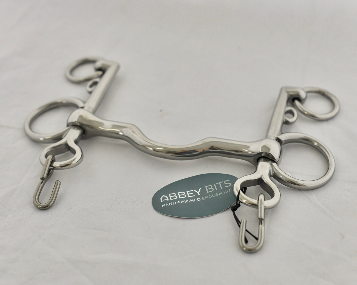 Close up of ported pelham horse bit on a white surface.