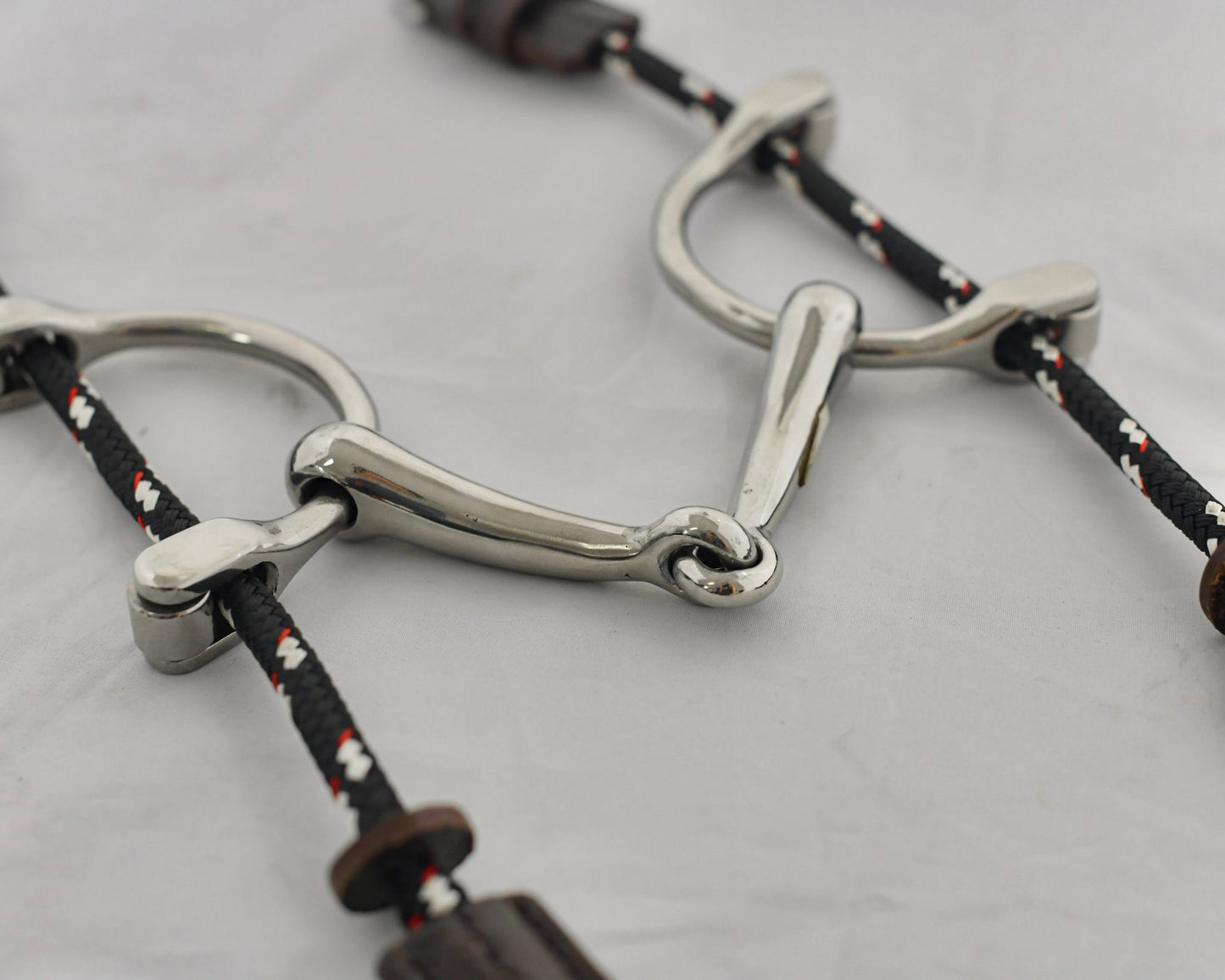 Close up of small balding gag horse bit on a white surface.