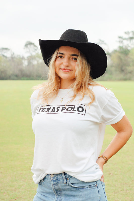 Girl wearing white t-shirt with black Texas Polo logo and a black cowboy hat.