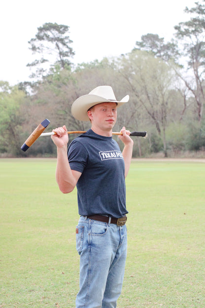 Man in a cowboy hat and navy Texas Polo t-shirt holding a polo mallet over his shoulders.
