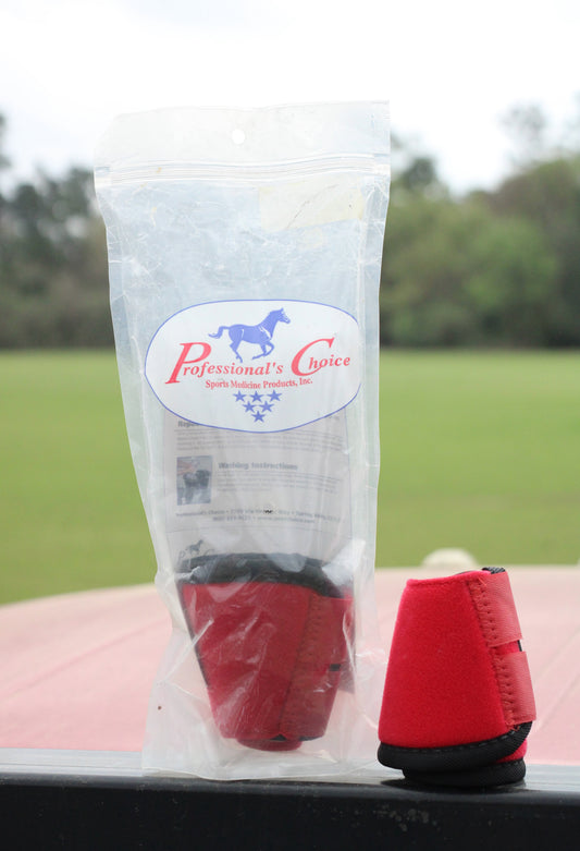 Two red bell boots for horse, with one sitting in a plastic bag and the other sitting next to it.