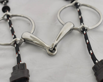 Close up of big ring gag horse bit on a white surface.