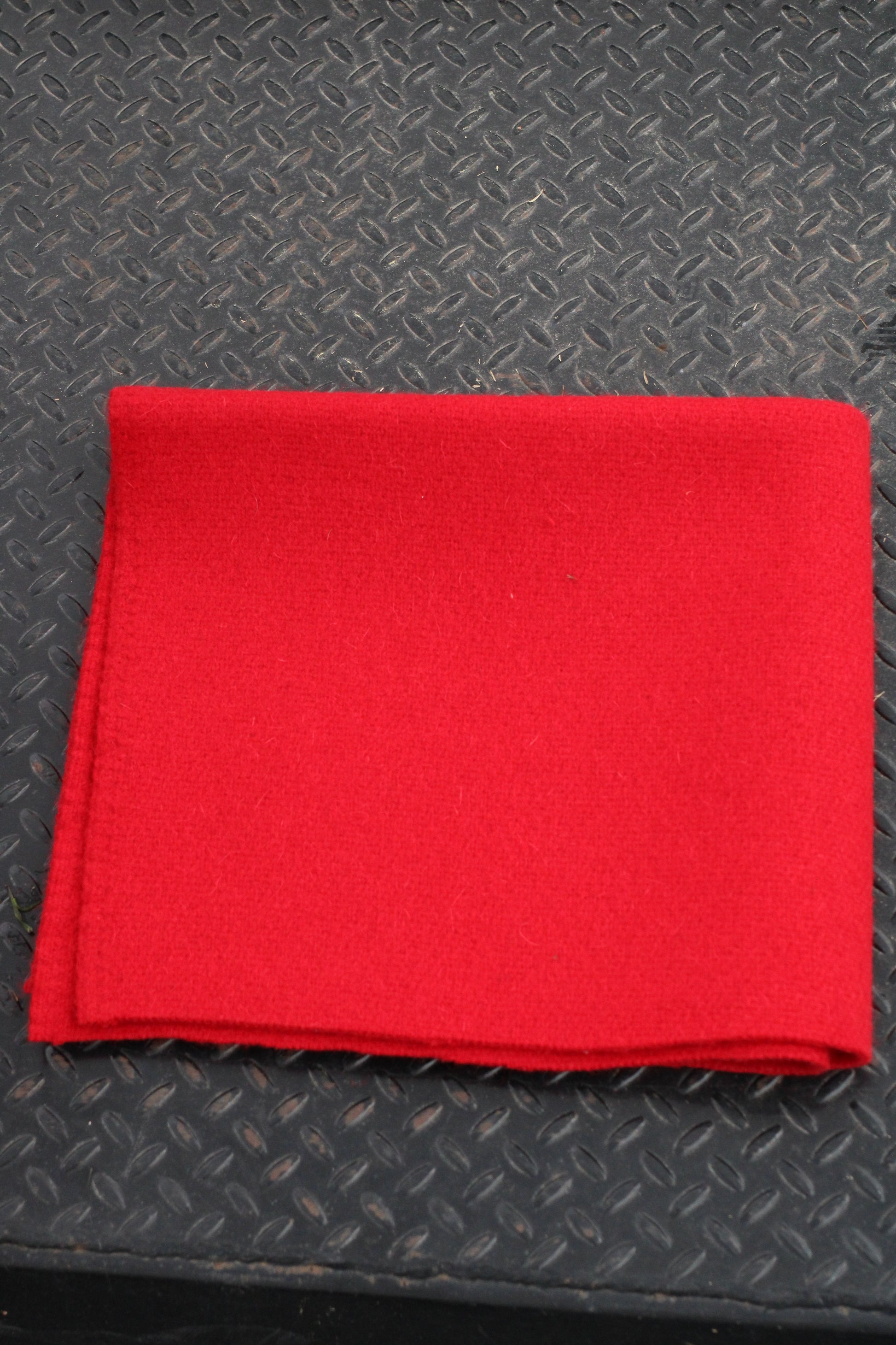 Red folded horse blanket sitting on a black surface.