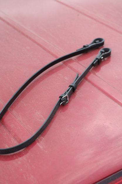 Leather bradoon hanger sitting on a red surface.
