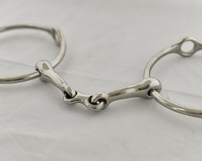 Close up of center link gag horse bit on a white surface.