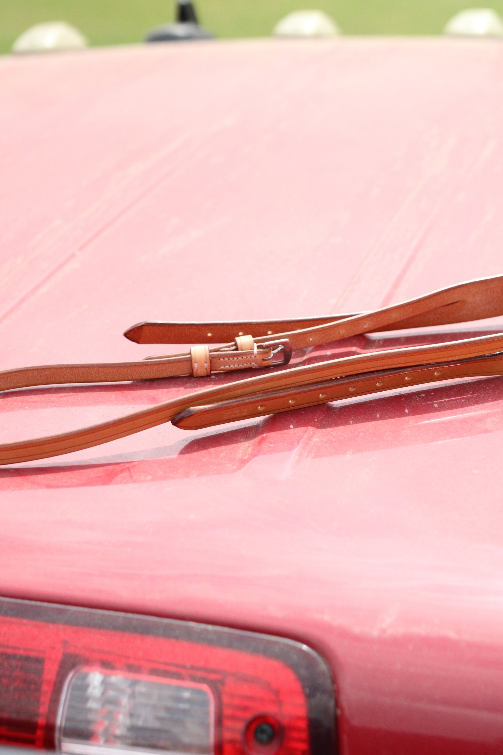 Side view of tan leather crown piece sitting on a red surface.