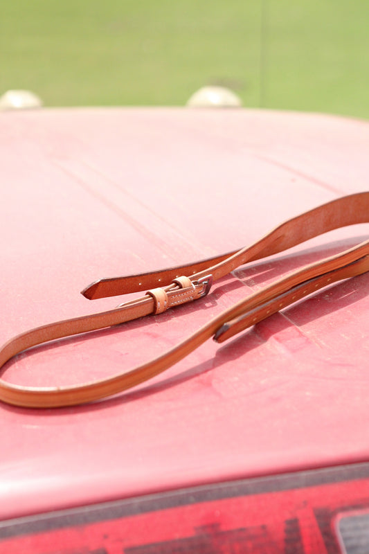 Tan leather crown piece sitting on a red surface.