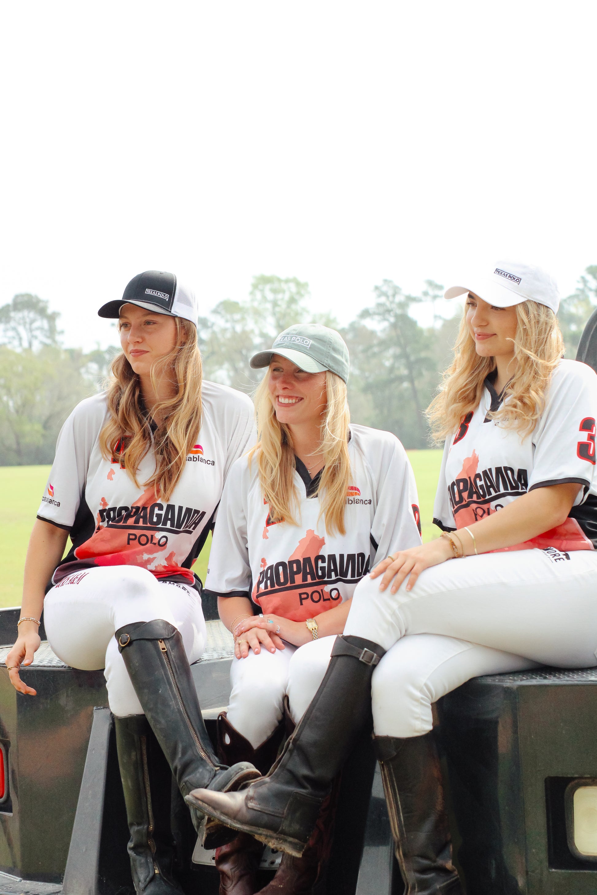 Three women wearing jerseys. The woman on the left is wearing a black and white mesh back Texas Polo hat. The woman in the middle is wearing a light green Texas Polo hat with a large logo. The woman on the right is wearing a white Texas Polo hat with a small logo.