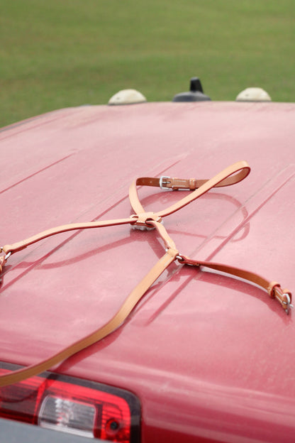 Tan leather figure 8 mouth tie sitting on a red surface.