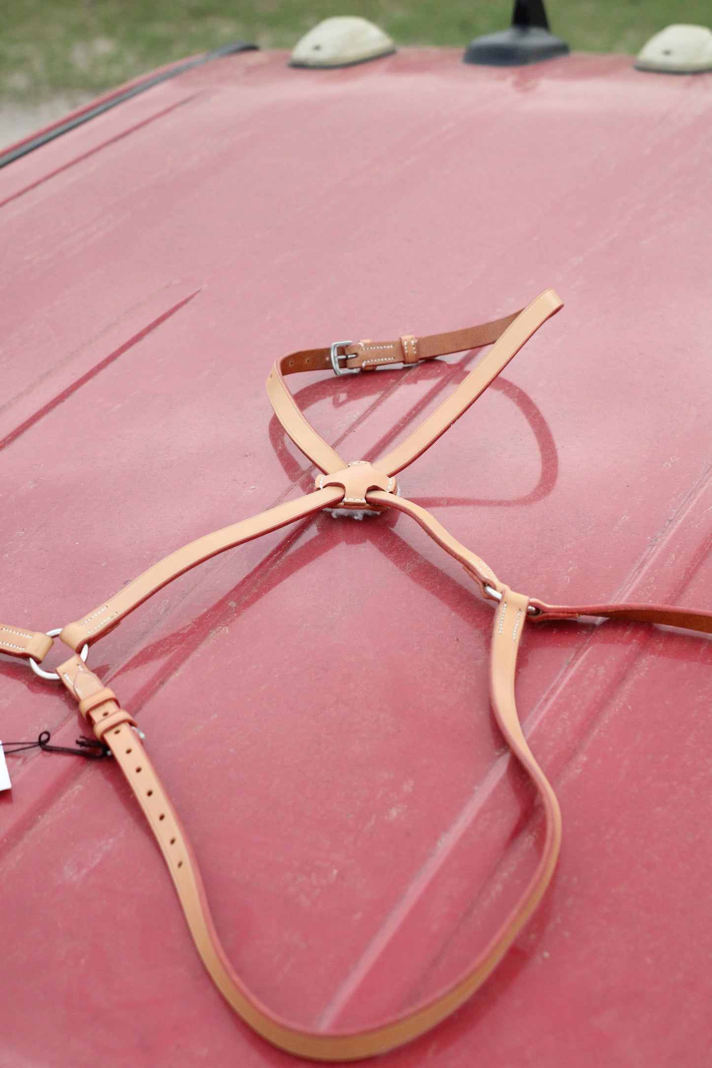 Full view of tan leather figure 8 mouth tie on a red surface.