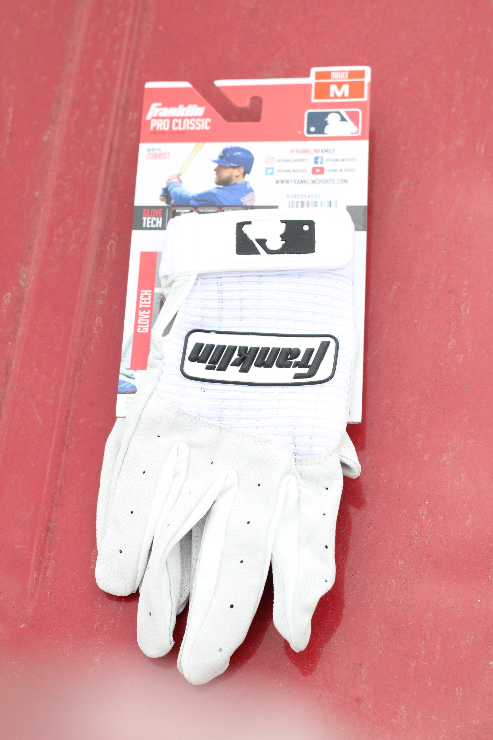 Pair of white athletic gloves sitting on a red surface.