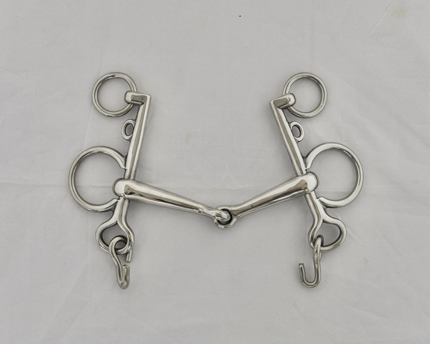 Jointed pelham horse bit on a white surface.
