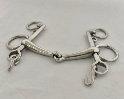 Close up of jointed pelham horse bit on a white surface.