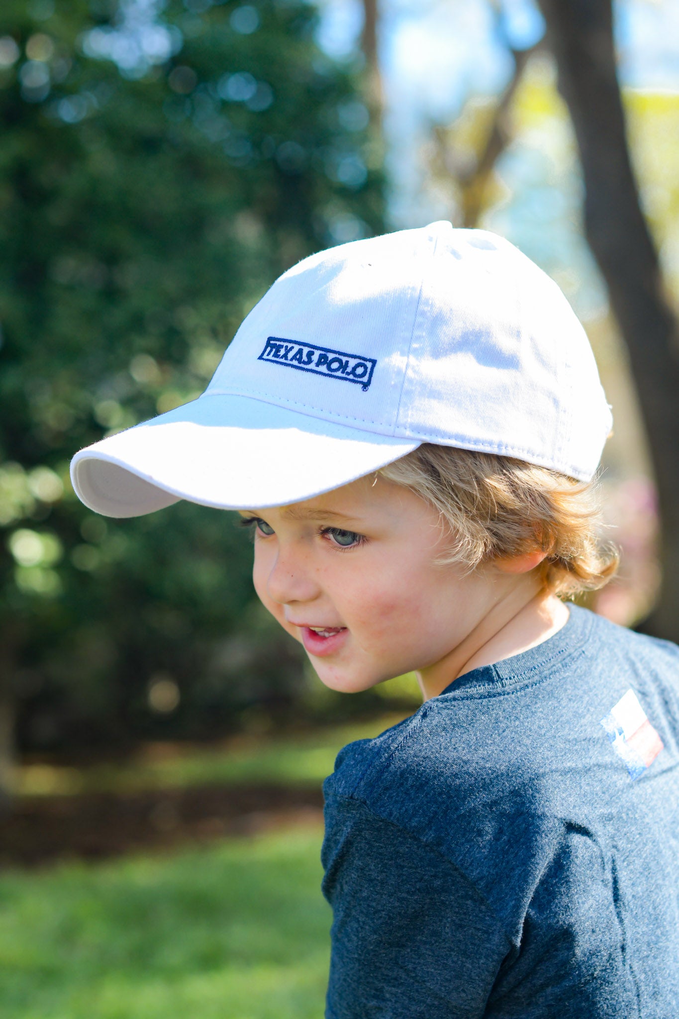 Child wearing white Texas Polo branded cap and navy Texas Polo t-shirt.