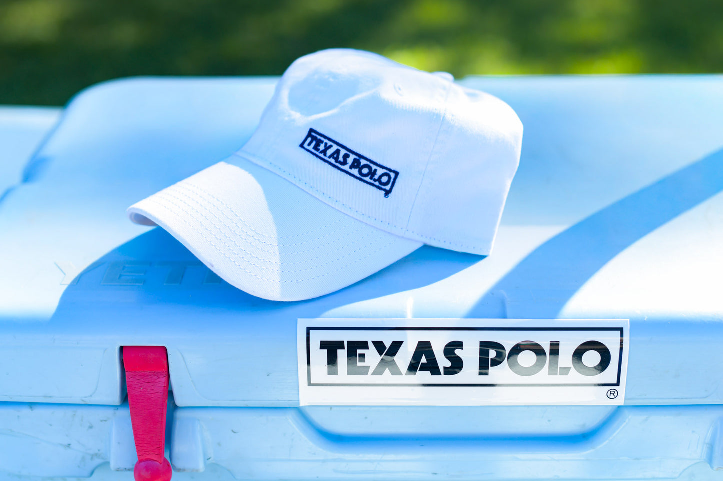 White Texas Polo branded cap sitting on top of a YETI cooler with a white Texas Polo sticker on it.