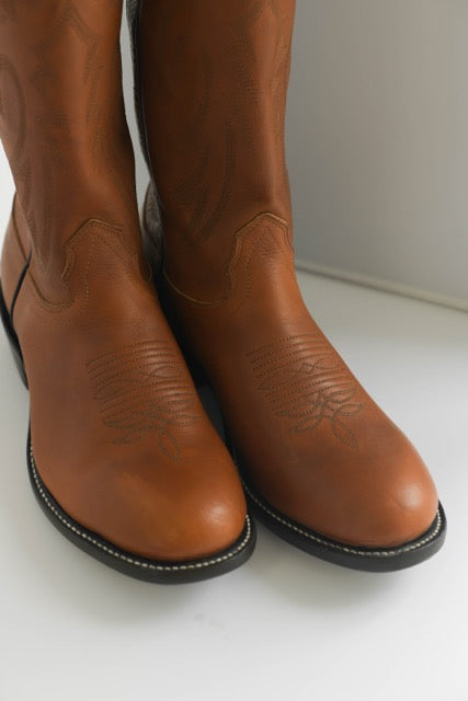 Closeup of the toes of a pair of brown leather boots.