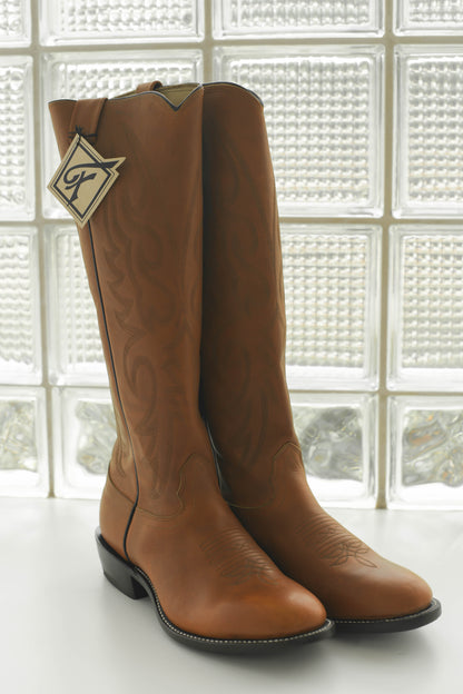 Pair of brown leather boots in front of a window.