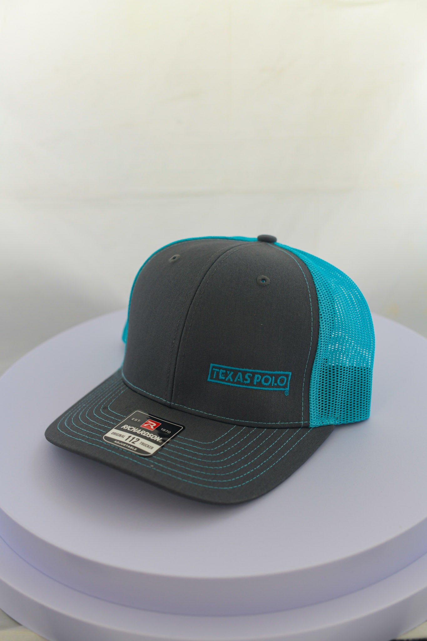 Grey and teal mesh back cap with small teal Texas Polo logo.