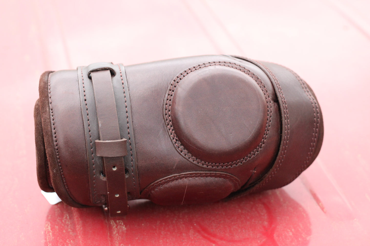 Brown leather knee guard sitting on a red surface.