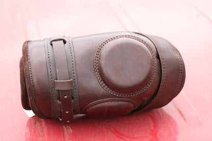 Brown leather knee guard sitting on a red surface.