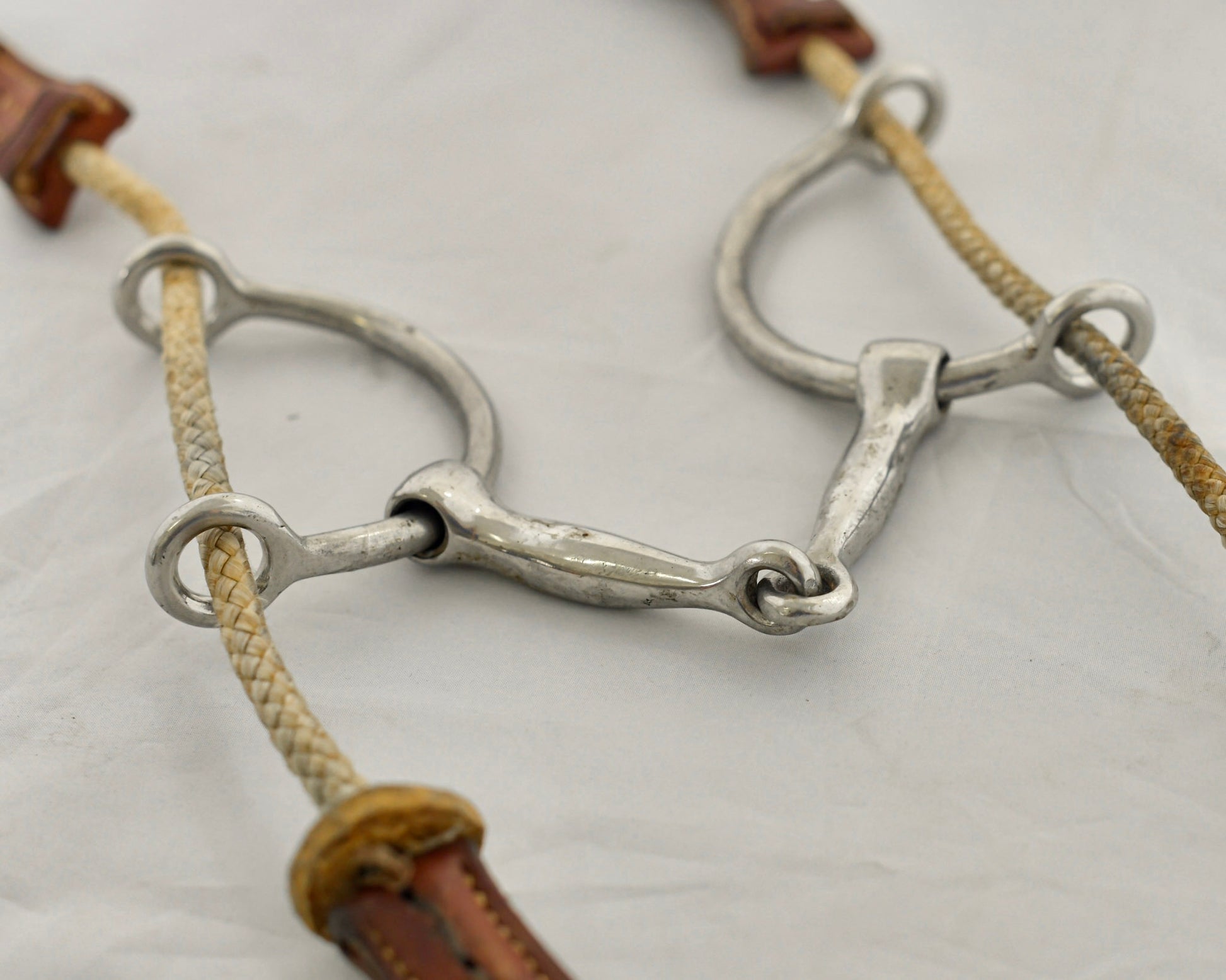 Close up of large balding gag horse bit on a white surface.