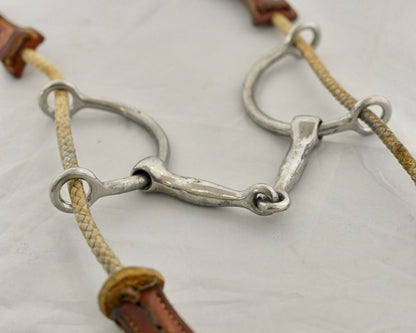 Close up of large balding gag horse bit on a white surface.