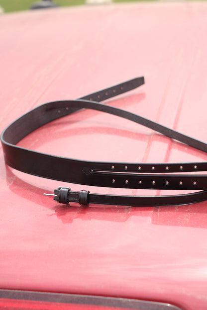 Black leather mouth tie sitting on a red surface.