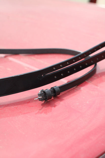 Close up of black leather mouth tie on a red surface.