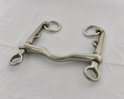 Close up of pelham horse bit on a white surface.