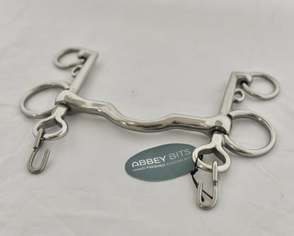 Close up of ported pelham horse bit on a white surface.
