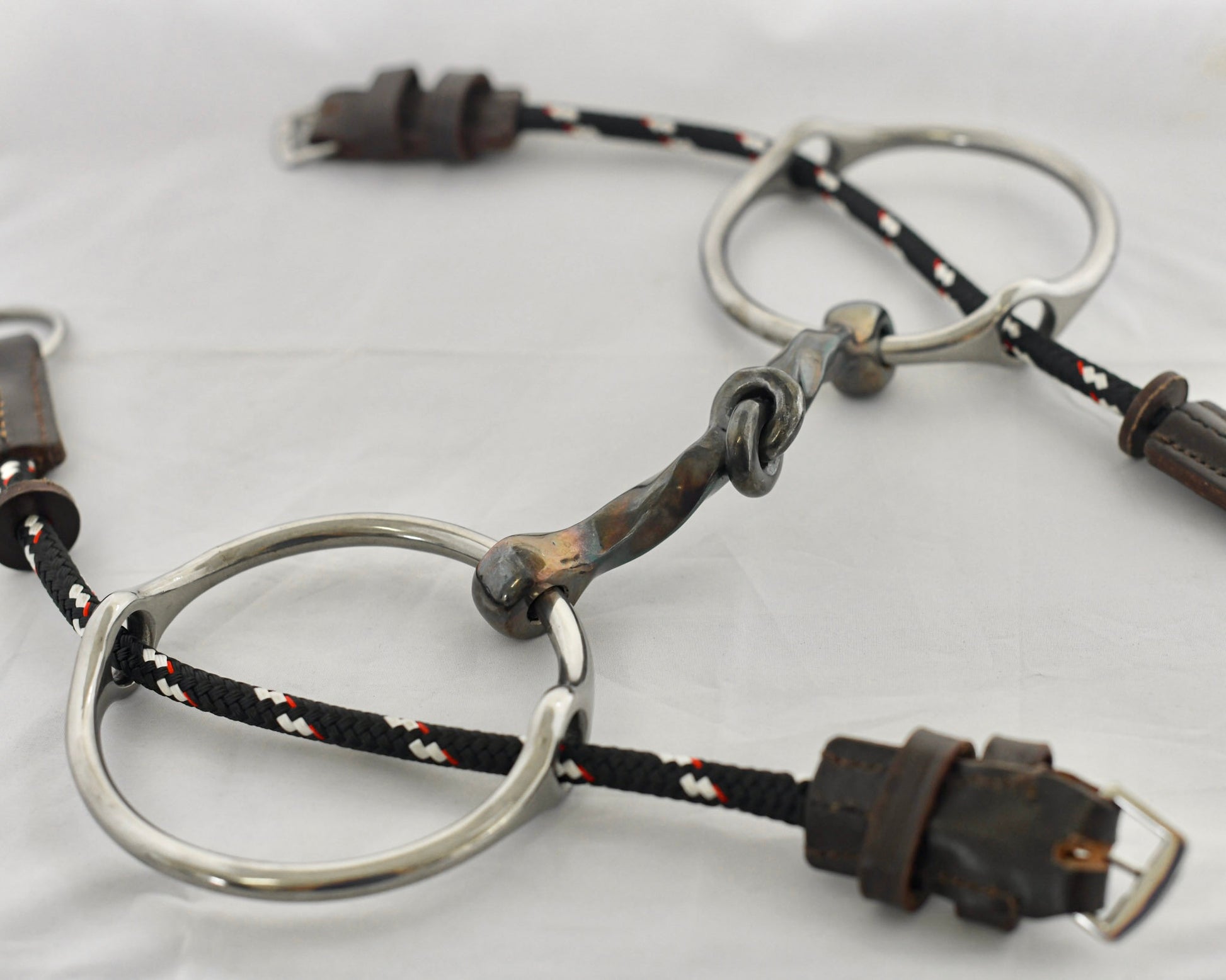 Close up of slow twist copper mouth gag horse bit on a white surface.