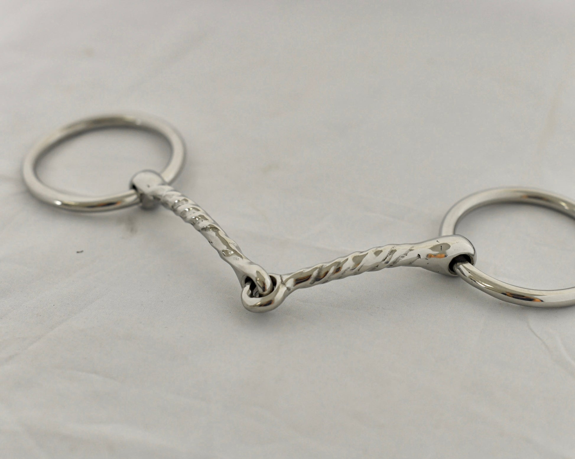 Close up of twisted badroon gag horse bit on a white surface.