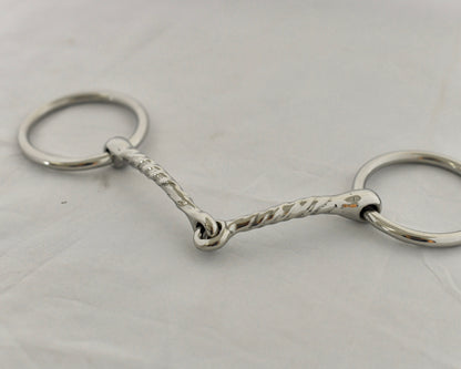 Close up of twisted badroon gag horse bit on a white surface.