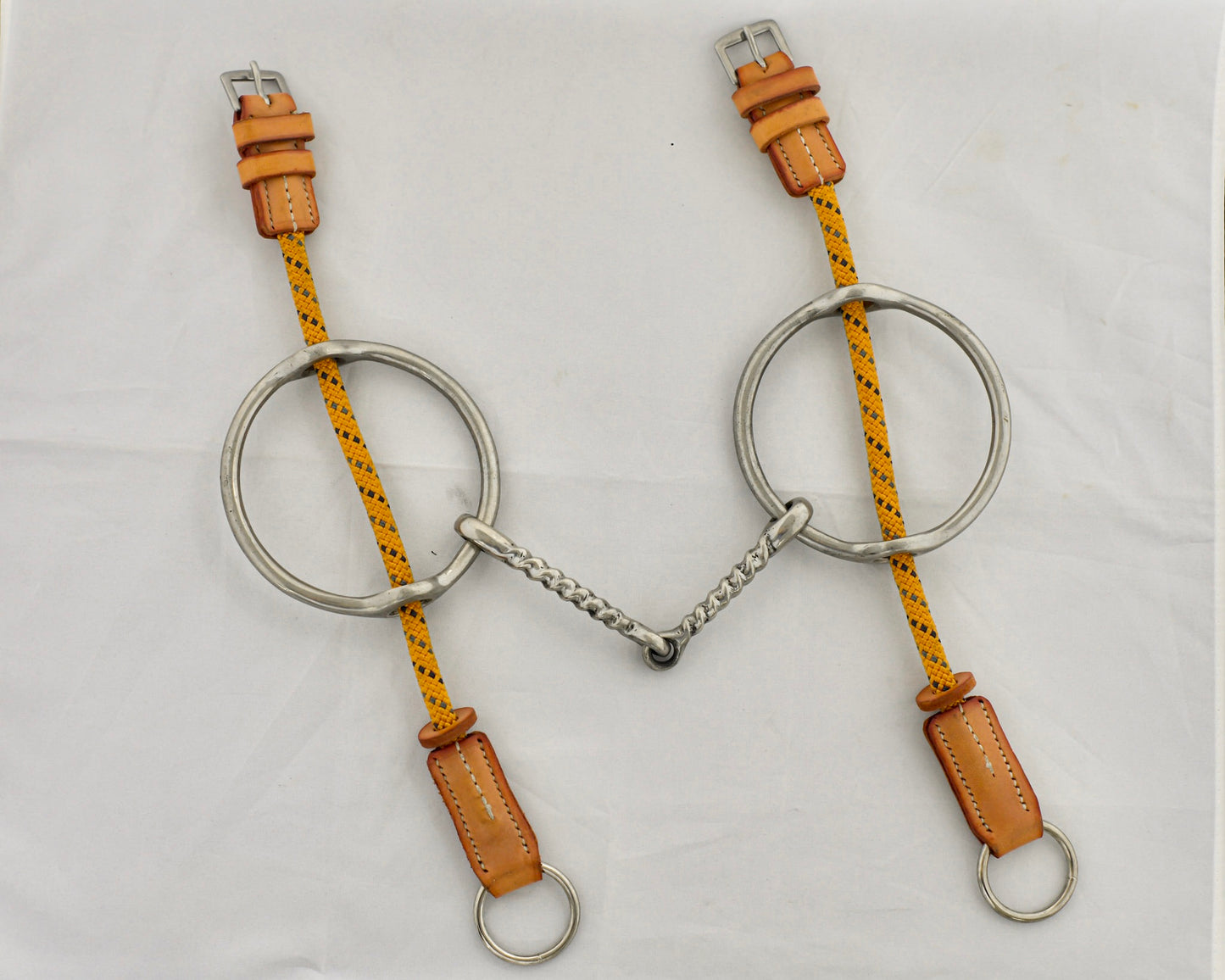 Twisted big ring gag horse bit on a white surface.