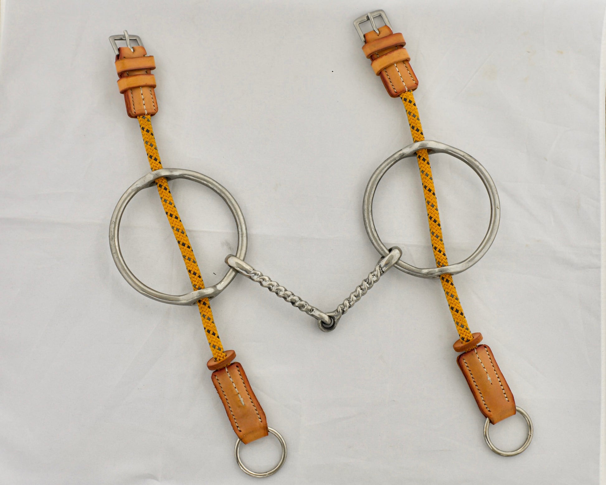 Twisted big ring gag horse bit on a white surface.