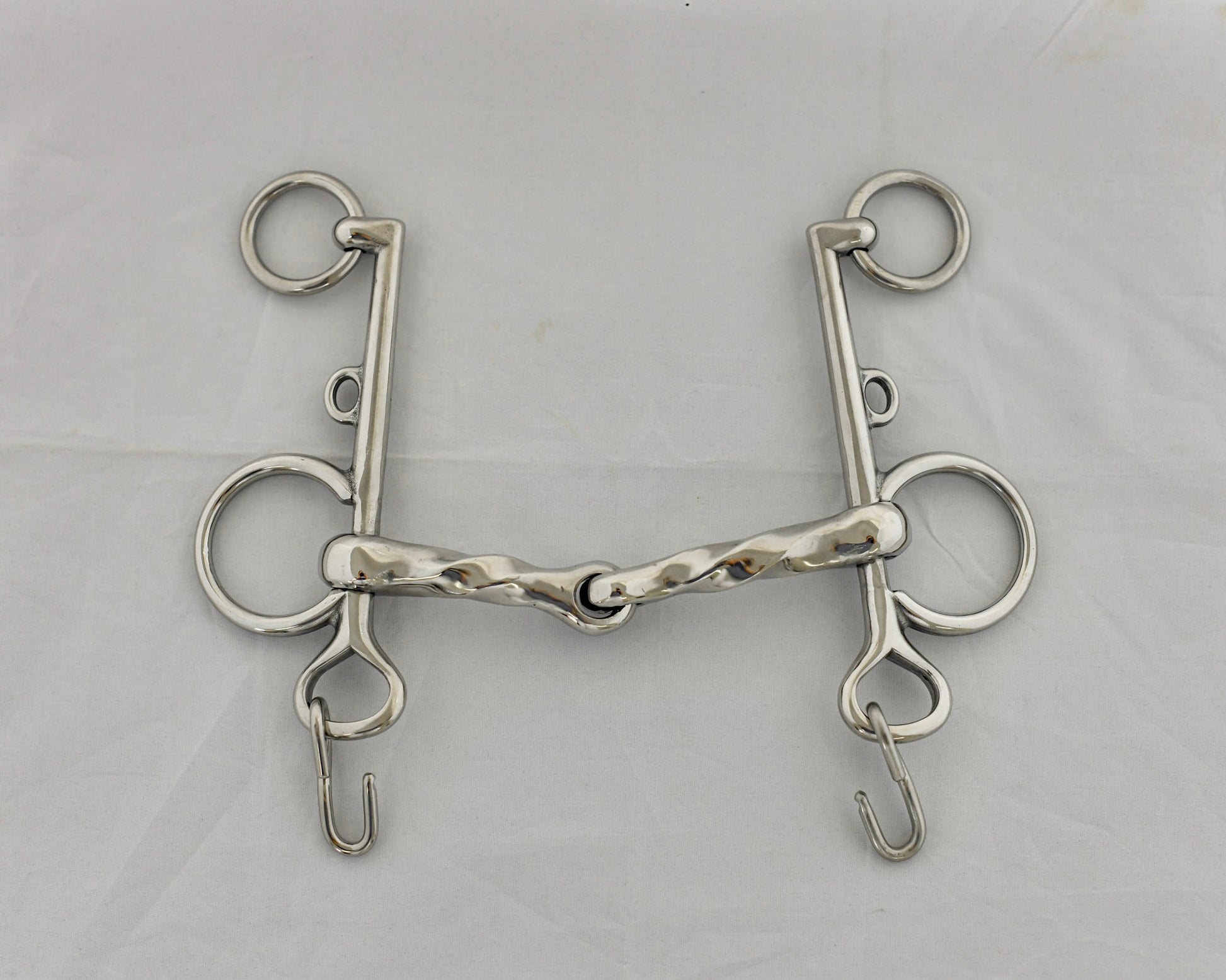 Twisted jointed pelham horse bit on a white surface.