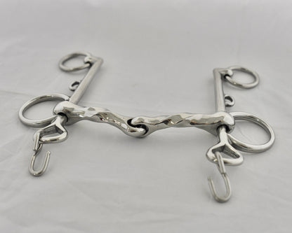 Close up of twisted jointed pelham horse bit on a white surface.