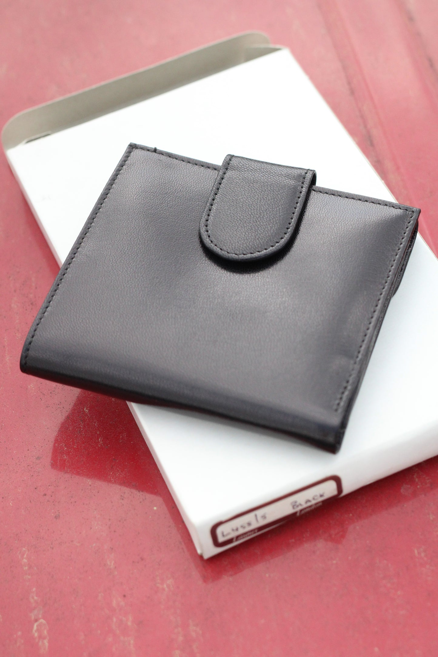 Closed leather bifold wallet with small snap closure.