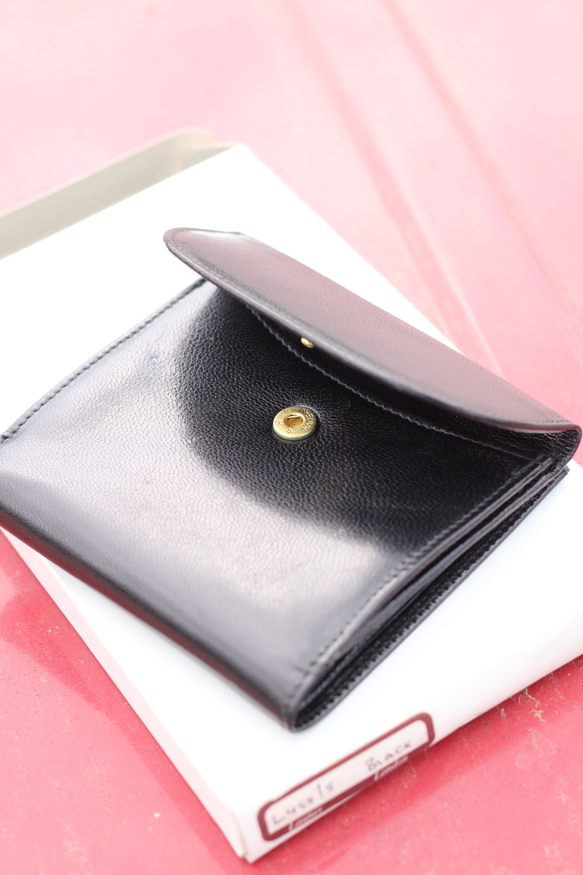 Leather bifold wallet with wide snap enclosure opened.