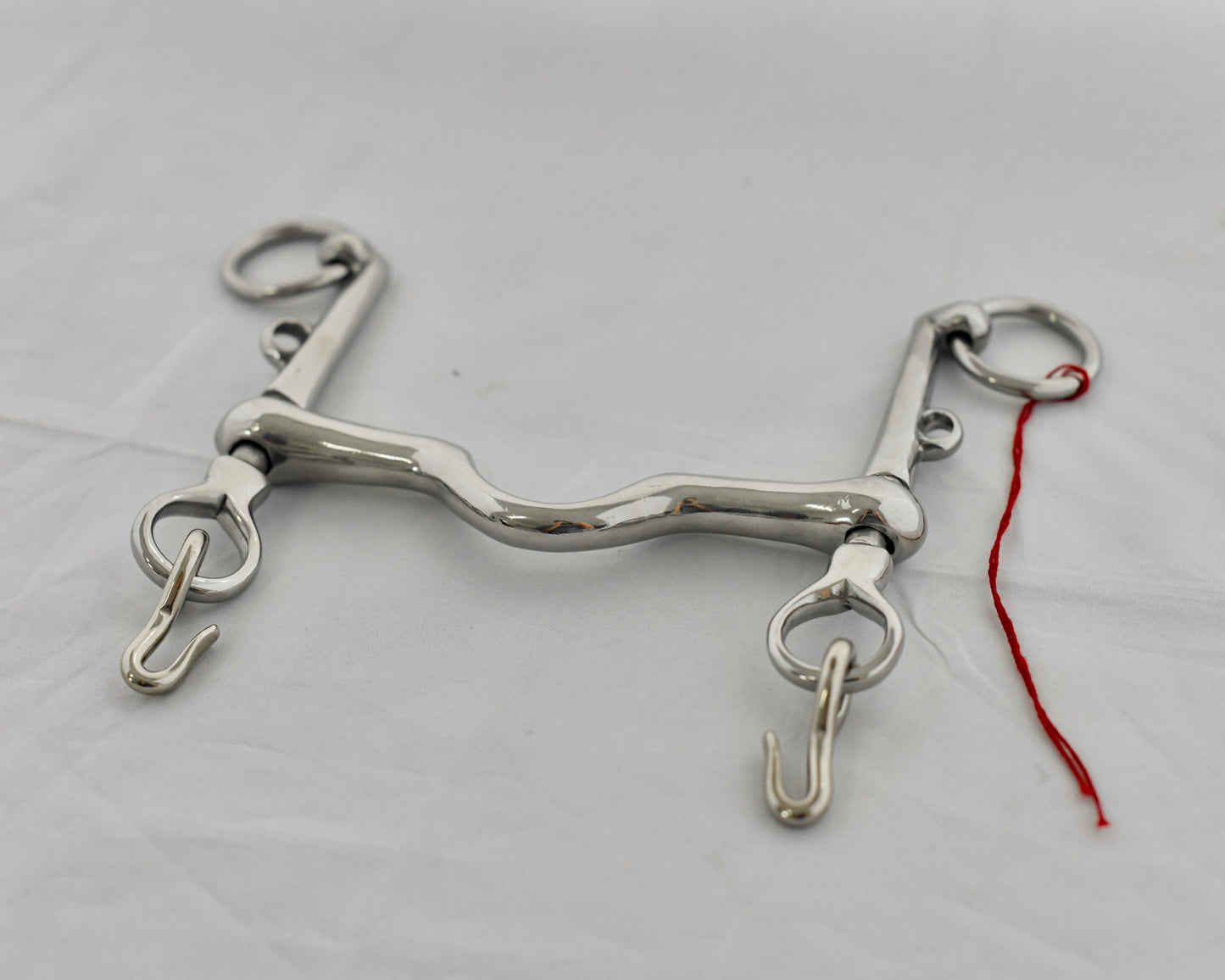 Close up of weymouth pelham horse bit on a white surface.