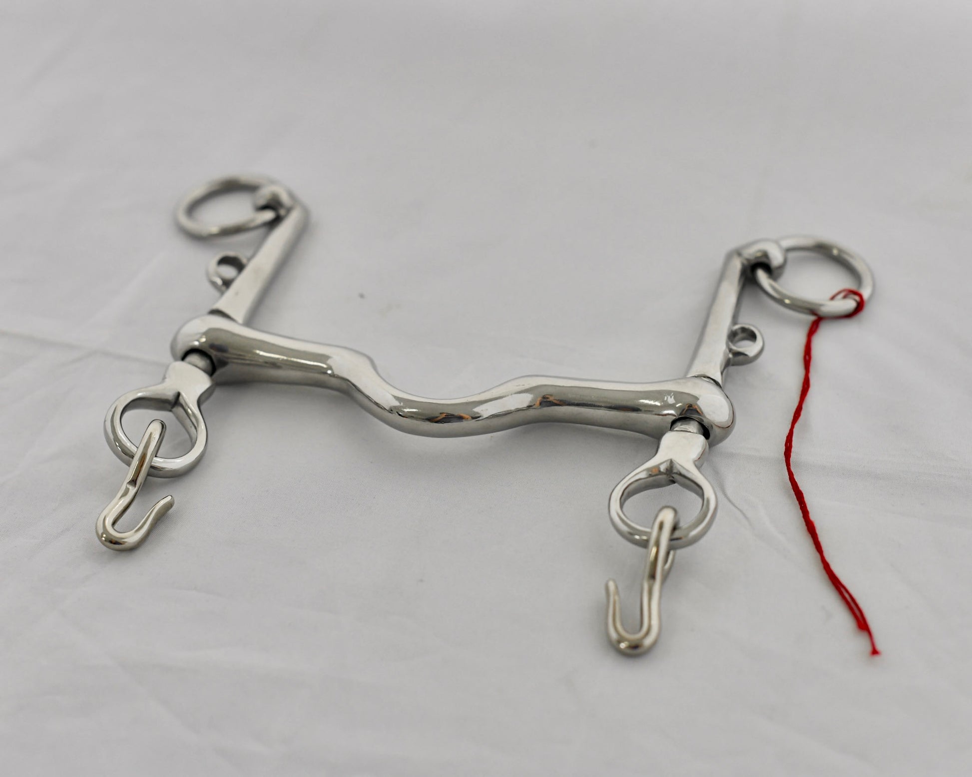 Close up of weymouth pelham horse bit on a white surface.
